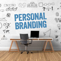 Personal Branding text on wall with a desk and computer under.